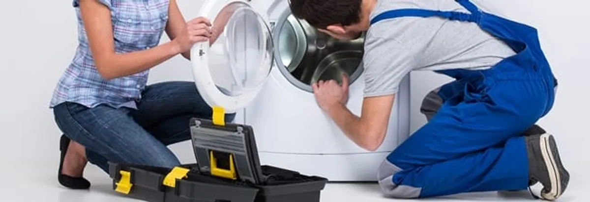 Washer repair technician inspecting a front-load washing machine with tools in Indianapolis, IN