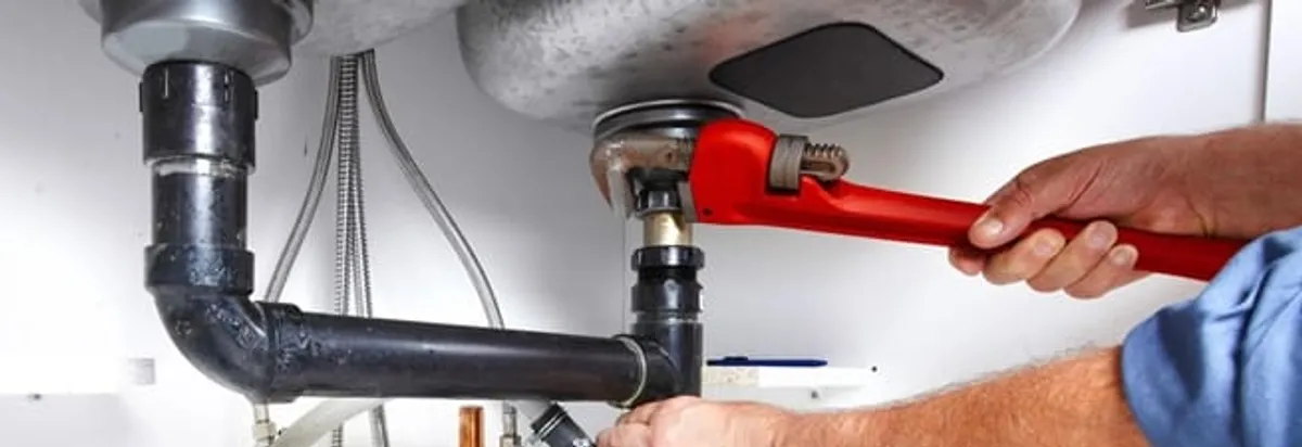 Garbage disposal repair technician tightening the sink drain and disposal connection in Indianapolis, IN