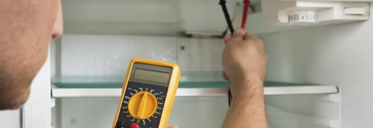 Refrigerator repair technician testing electrical components with a multimeter in Indianapolis, IN