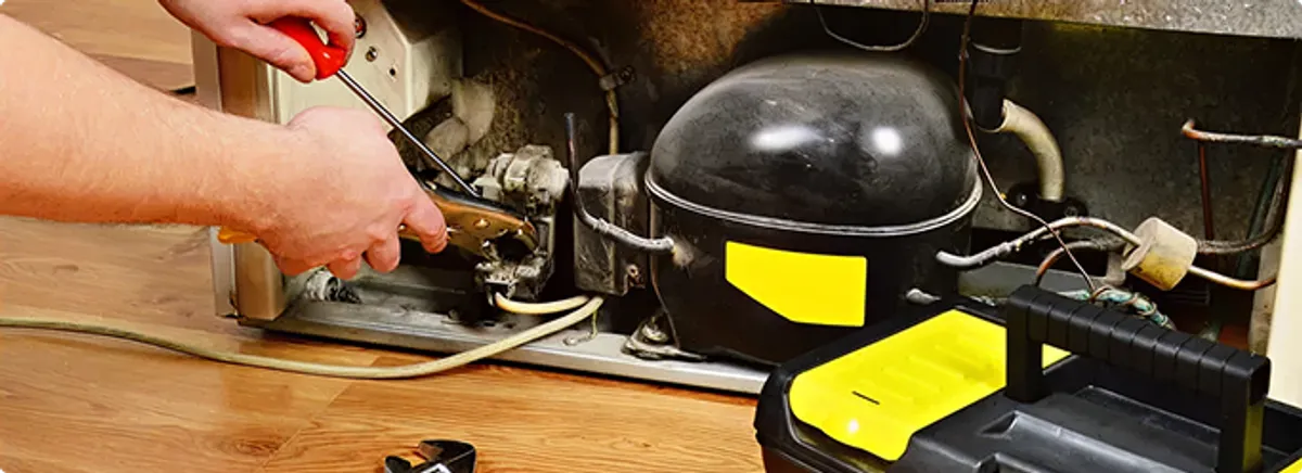 Refrigerator repair technician fixing the compressor and wiring in Indianapolis, IN