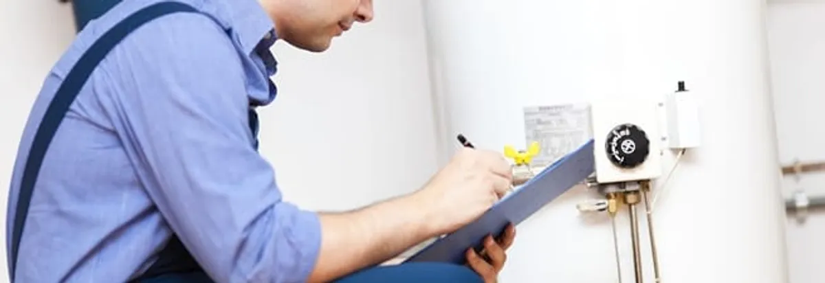 Water heater repair technician inspecting the unit and recording service notes in Indianapolis, IN